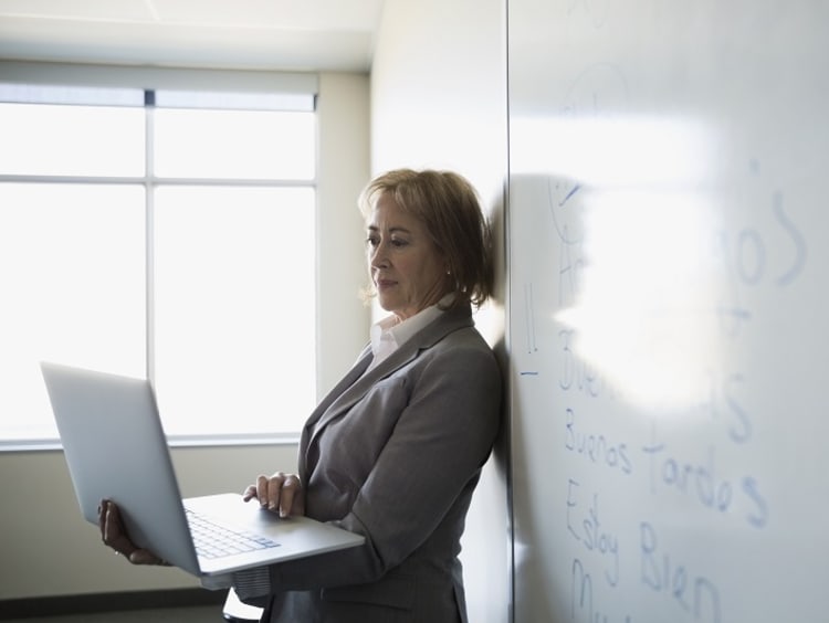 Spanish teacher working on laptop in front of whiteboard