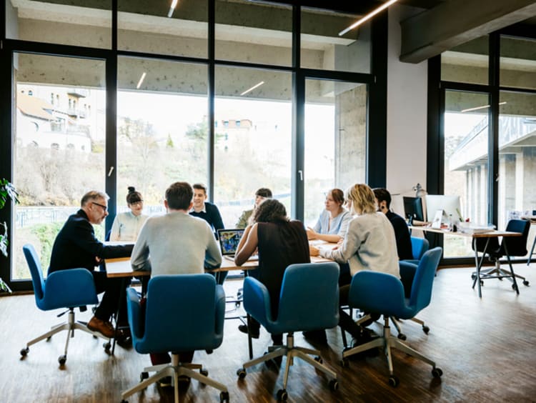 Business meeting in a large board room with tall windows