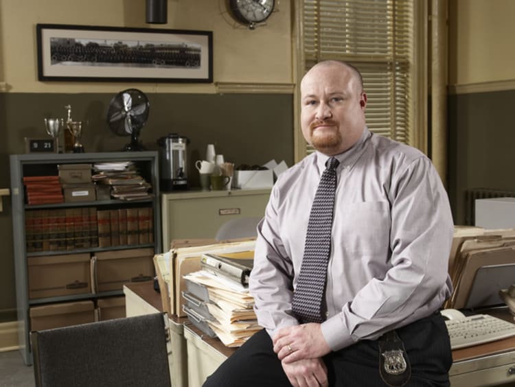 private investigator sitting on desk in office