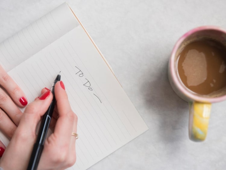 Writing on a piece of paper with coffee nearby