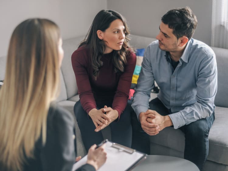 Couple sitting across from counselor on sofa