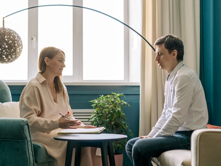 Female Christian counselor speaking with male client in office