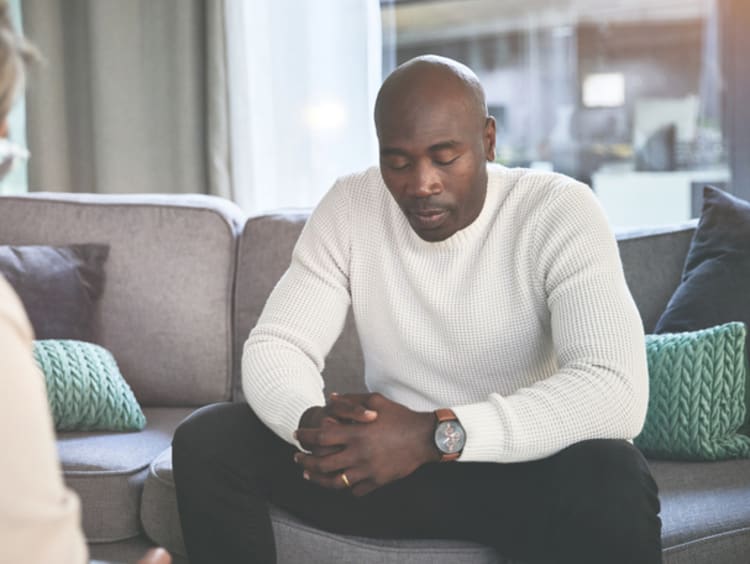 Man sitting on a couch talking with a grief counselor