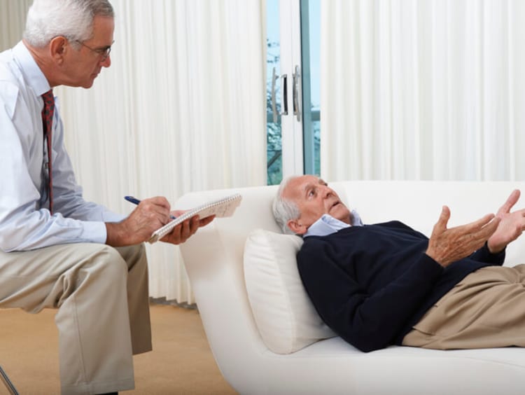 Psychologist psychoanalyzes patient on white couch near window