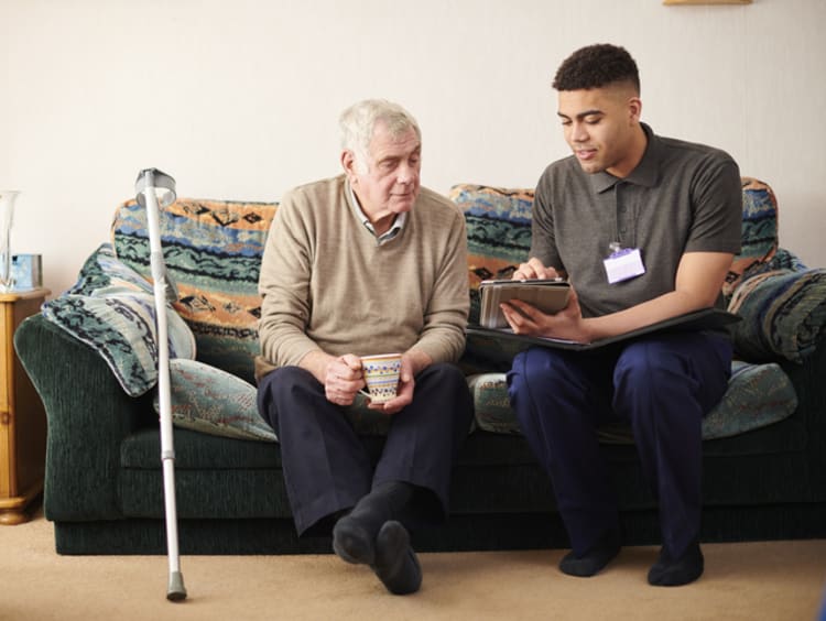 young male social worker meeting with elderly male client on couch