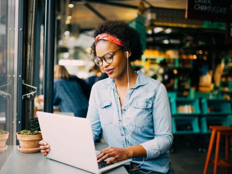 Woman studying at a coffee shop with a laptop and glasses