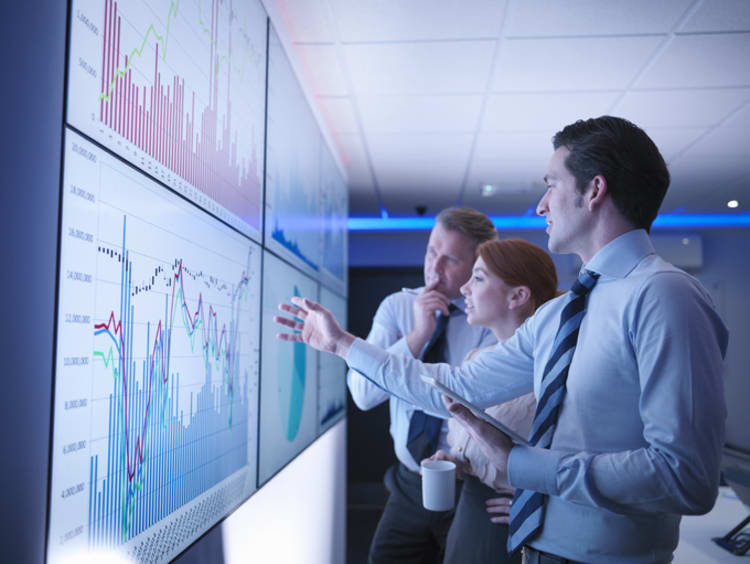 Business associates gather around a group of monitors 