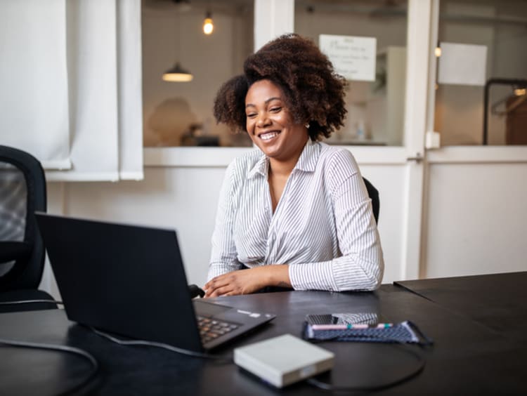 Businesswoman smiling while looking at laptop