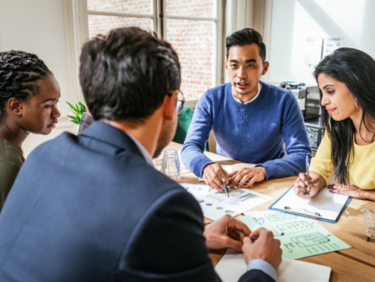 Financial manager sitting down with team and discussing paperwork