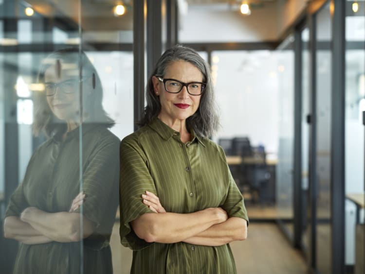 Smiling entrepreneur leaning against a glass wall