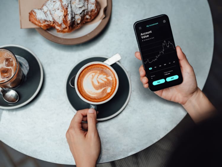 Person investing on their phone in coffee shop