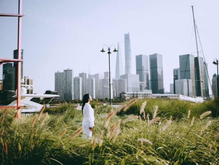 Woman standing in grass field looking at the city