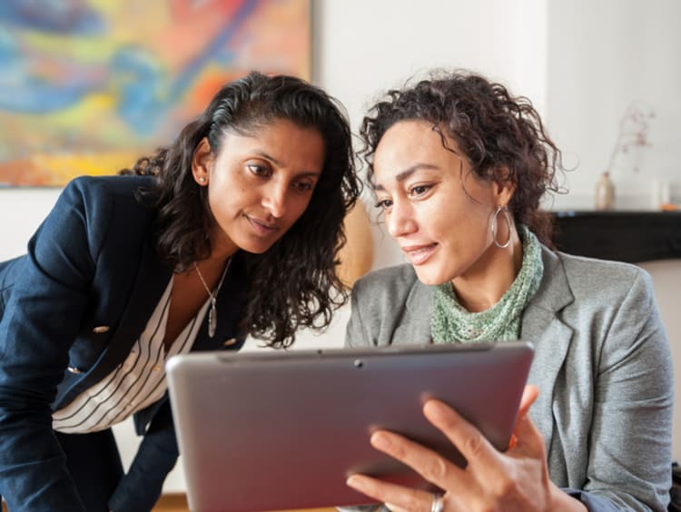 Diversity and inclusion specialist discussing information on tablet with coworker