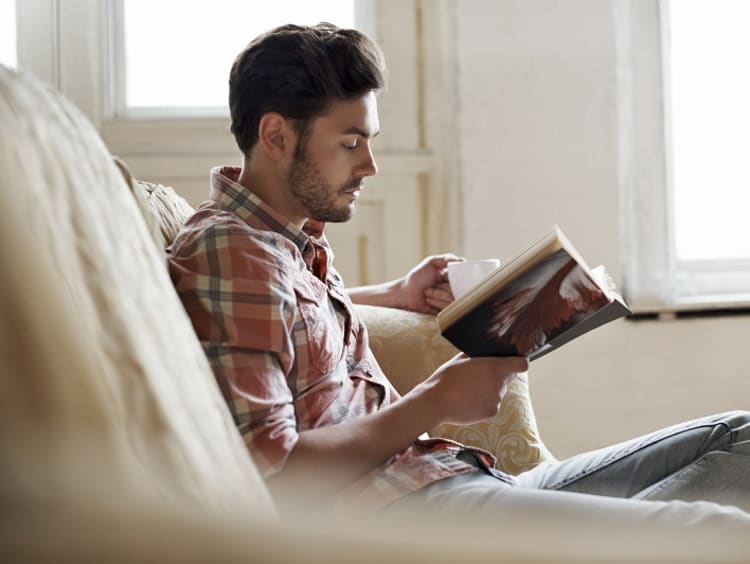 Man reading with a drink on a couch