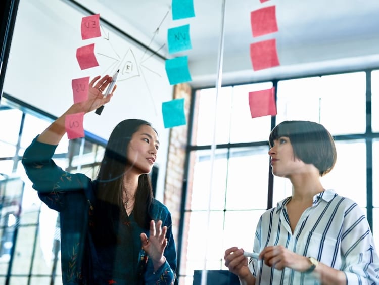 Two coworkers organizing sticky notes in midair