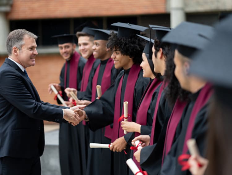 Academic dean shaking graduates hands