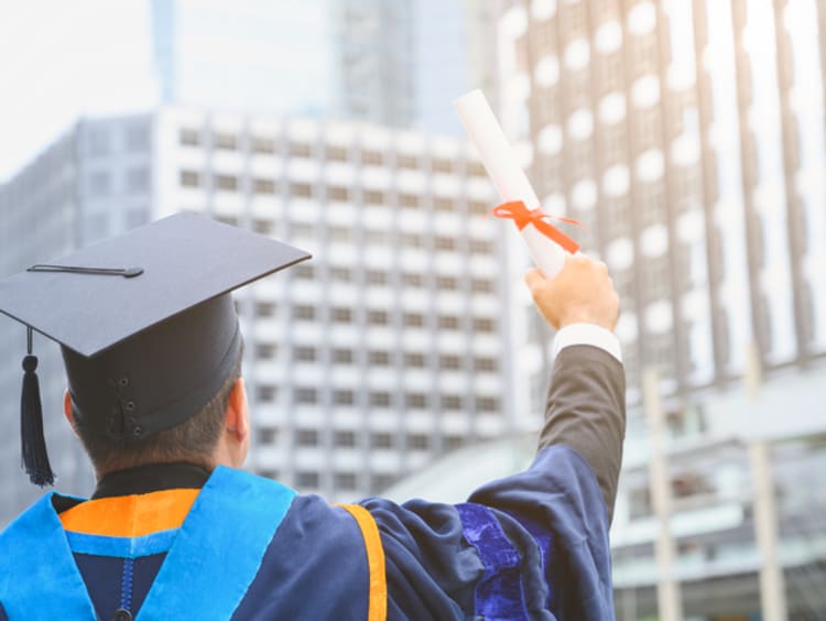 A PhD student holding up his diploma 