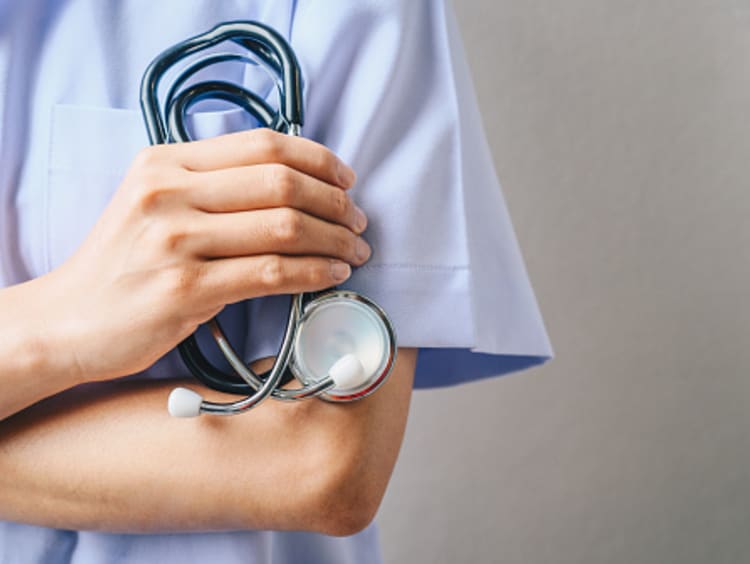 DNP student in scrubs holding stethoscope