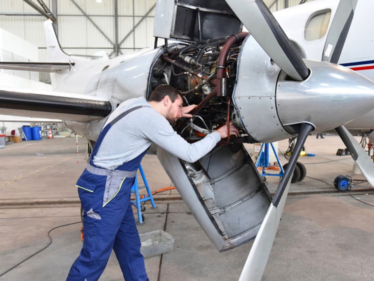 Aerospace mechanic repairing aircraft engine 