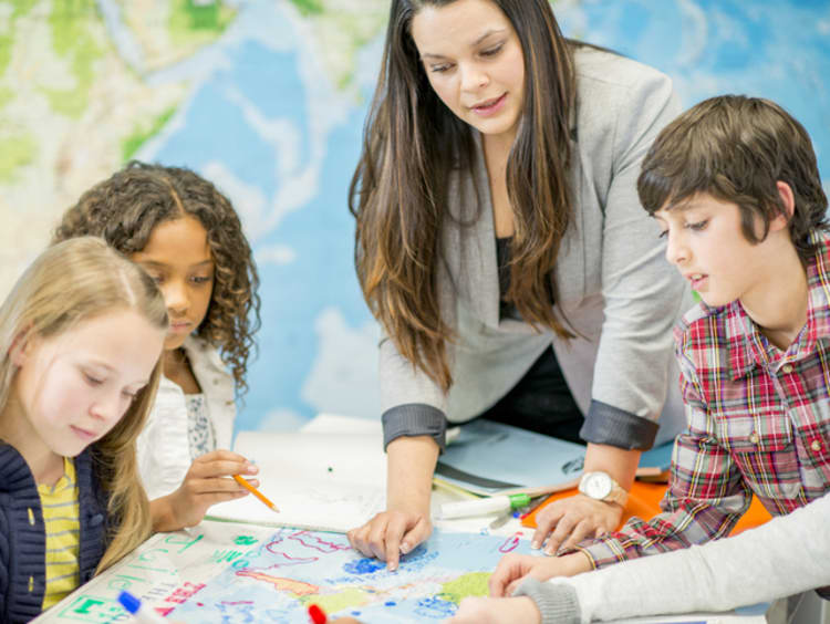 A history teacher helping her students find locations on a map