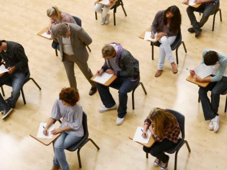 Teacher watching several students taking test in auditorium