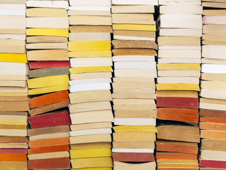 A stack of books in warm colors against a wall