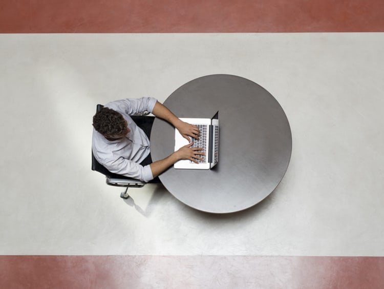 A college student working on his laptop by himself