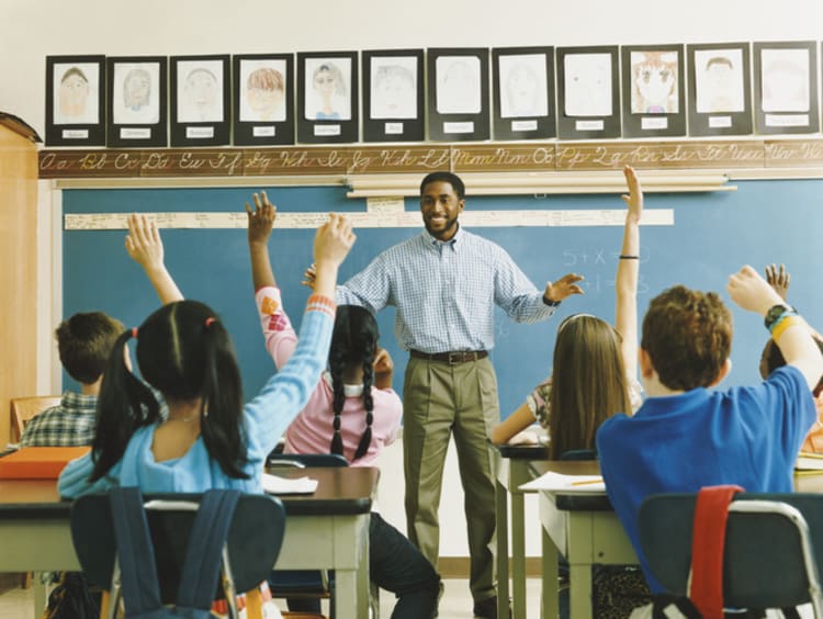 A classroom full of students raising their hands to answer a question