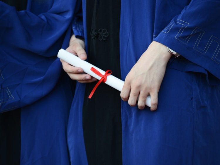 A college graduate in a gown holding a diploma