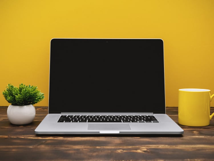 A student's laptop against a yellow background