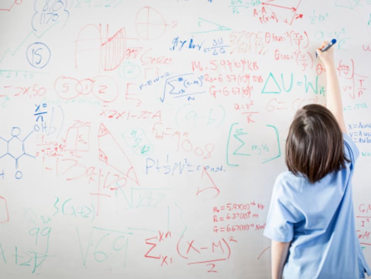 A student writing equations on a white board