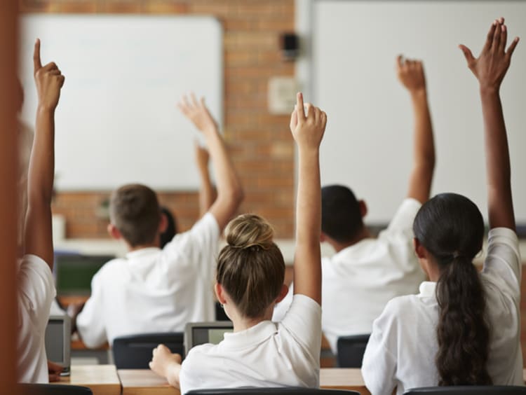 High school students raising their hands in class