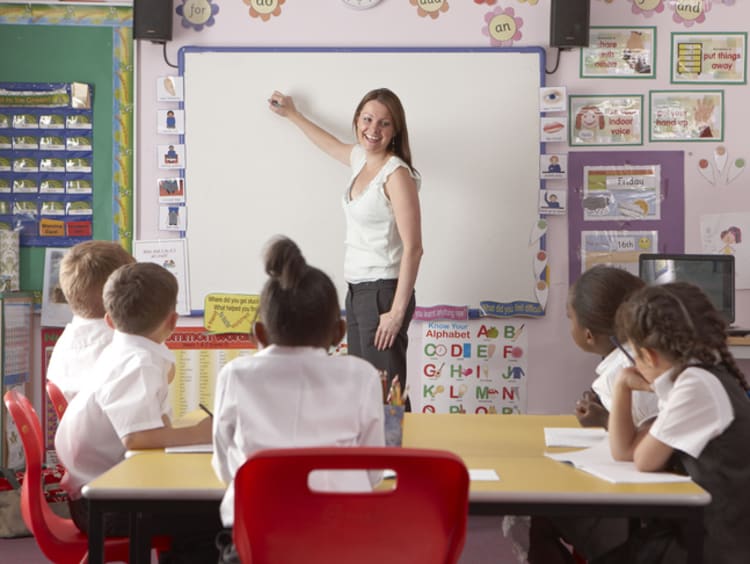 A group of diverse students learning from a teacher at a whiteboard