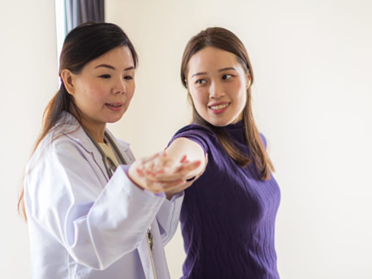 Female exercise physiologist examines female patient in office