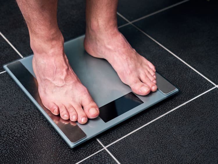 Fat man measuring his weight on a scale. top view.bare feet of an overweight  man