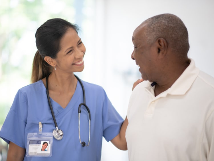 Female adult-gerontology nurse talking with male patient