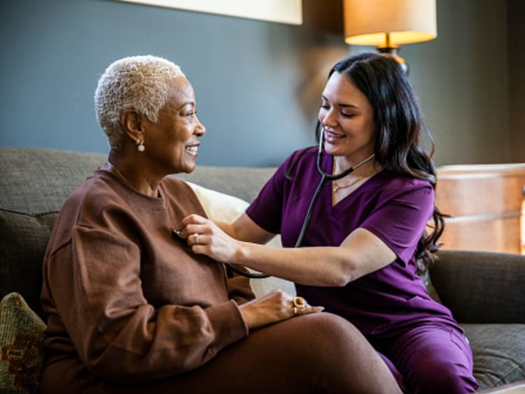 Public health nurse listening to woman's heart