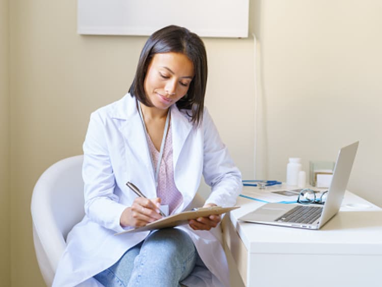 An Advanced Practice Registered Nurse taking notes on a clipboard