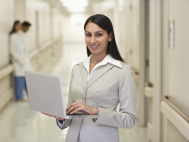 A healthcare administrator holding a laptop