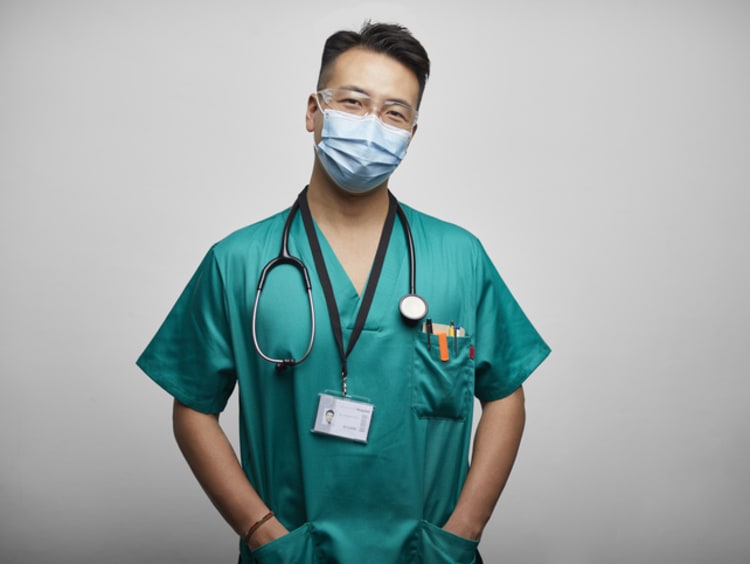 headshot of male nurse wearing mask and scrubs