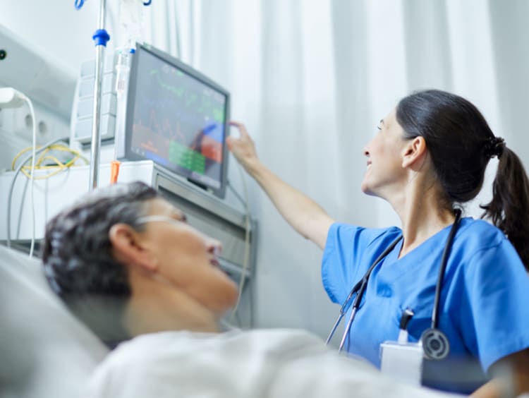 An acute care nurse checking the vitals of a patient