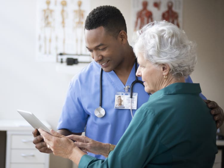 Male nurse reviewing information with elderly female patient.