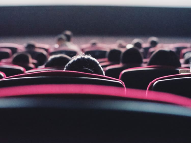 Chairs with people watching a movie in the theater