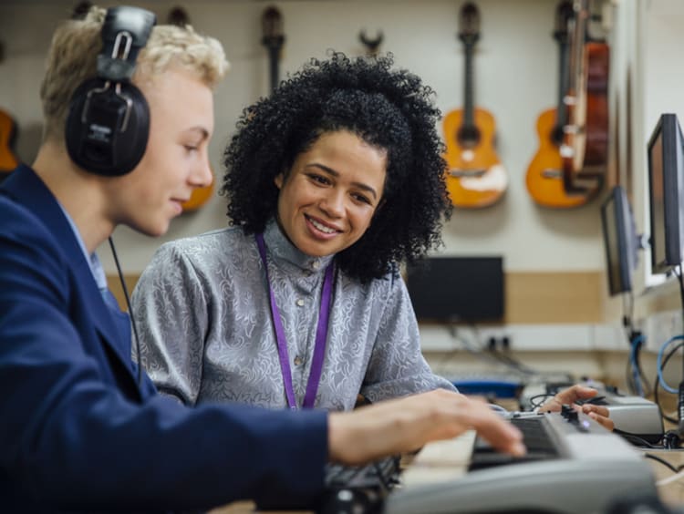 School music teacher helping student learn keyboard