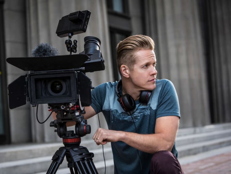 man kneeling next to a camera during filming