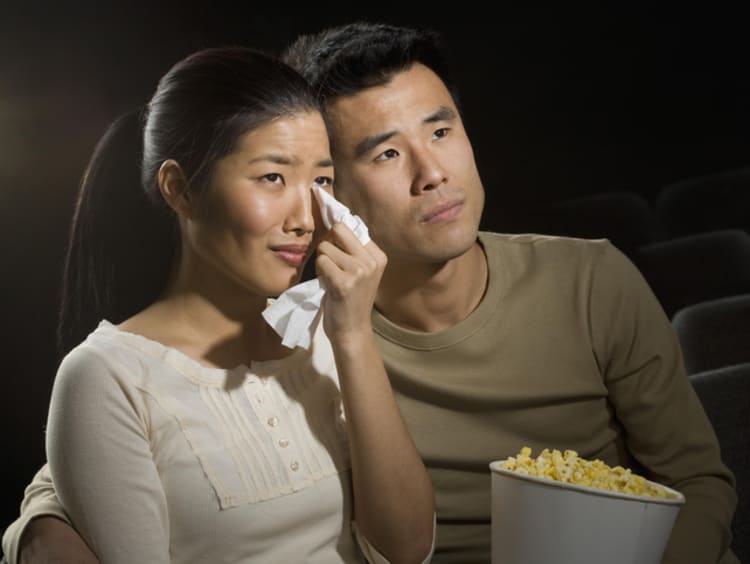 Couple watching movie in theatre that is making them cry