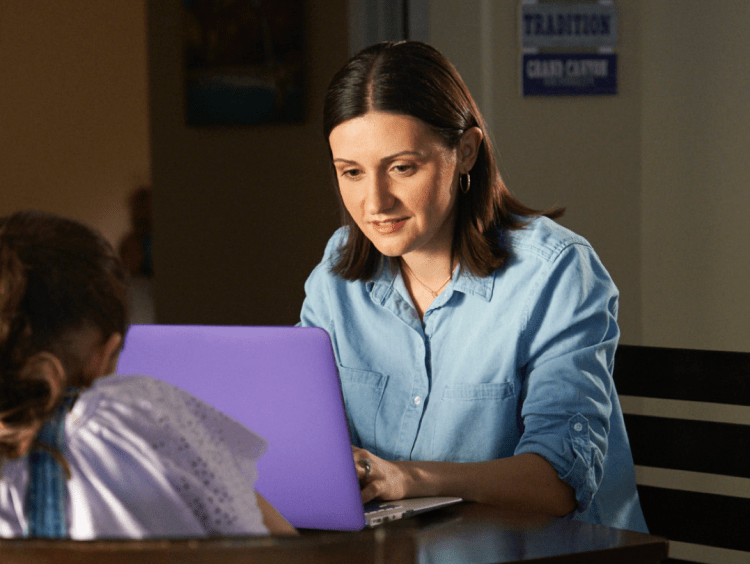 Woman teacher speaks with girl student in office setting