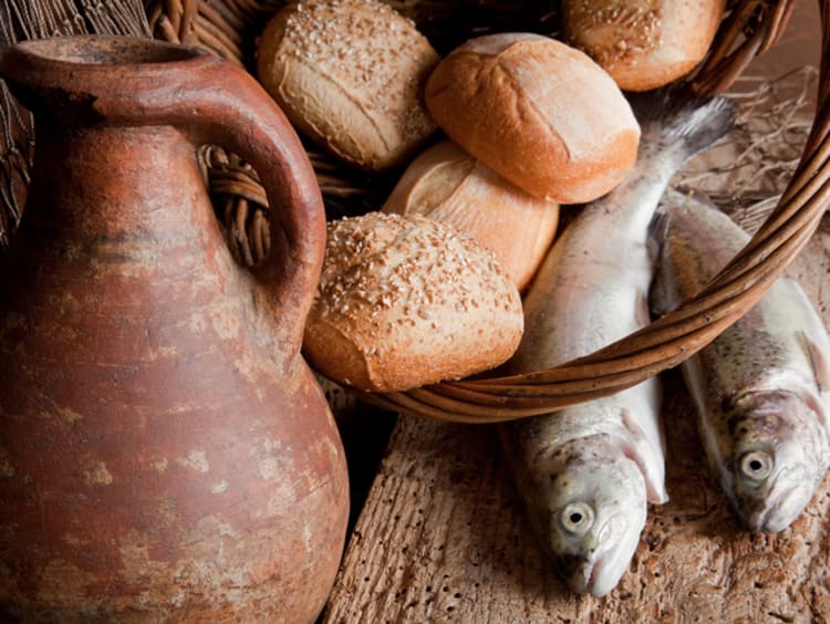 Loaves of bread and fish with old clay pitcher as a model for one of the miracles of Jesus