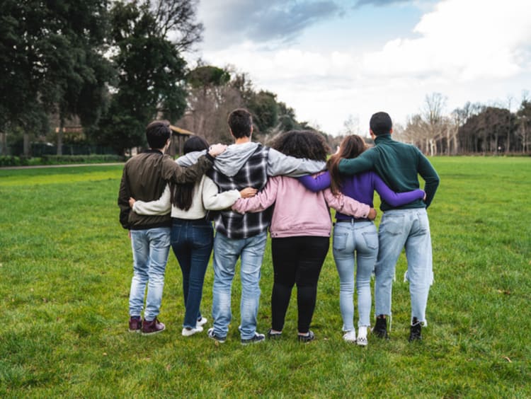 Godly friends supporting each other with interlinked arms on a grassy field