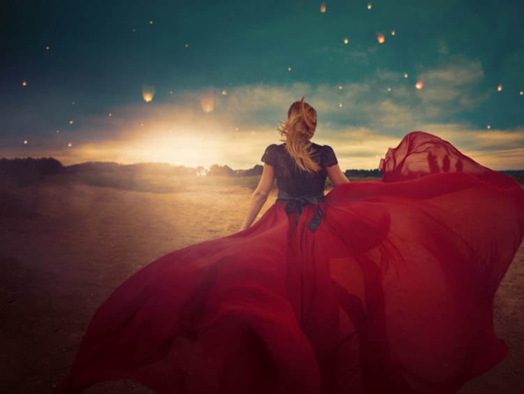 girl standing in field and dress flowing in the wind